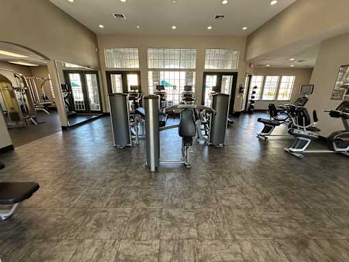 A gym with a variety of equipment including treadmills, weights, and exercise machines.