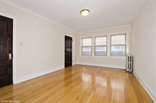 an empty living room with wood floors and a black door