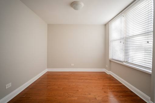 A room with wooden floors and a window with blinds.