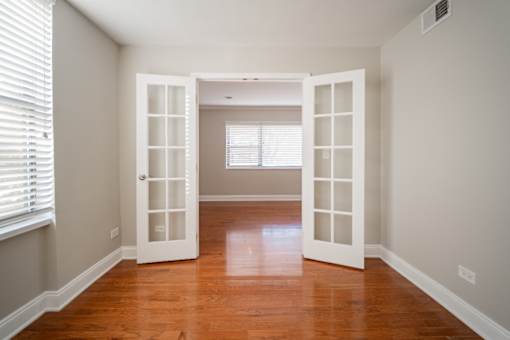 A room with a wooden floor and two open white doors.