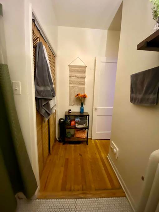 A hallway with a coat rack and a small table with flowers on it.