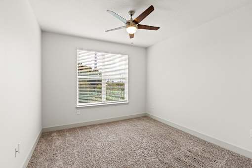 A room with a ceiling fan and a window with blinds.