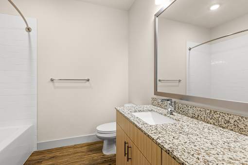 A bathroom with a toilet, sink, and mirror.