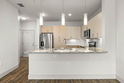 A kitchen with a granite countertop and wooden cabinets.