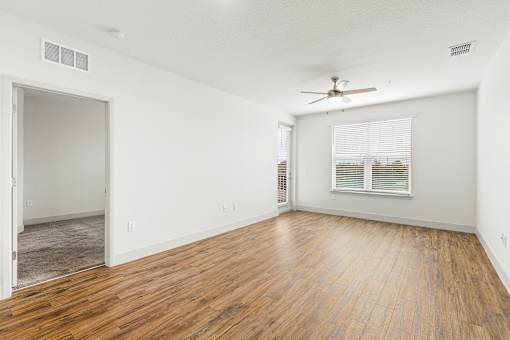 A room with a ceiling fan and a window with blinds.