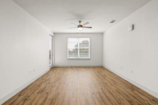 A room with a ceiling fan and wooden flooring.