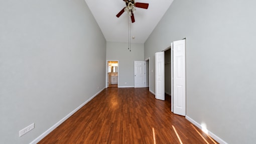 A room with a ceiling fan and wooden flooring.