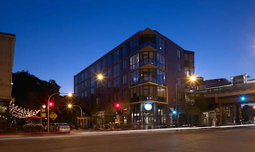 A modern building with a glass facade is illuminated by street lights at night.