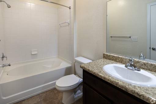 A white toilet sits next to a bathtub in a bathroom.
