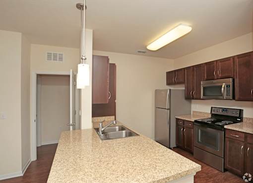 A kitchen with a granite counter top and stainless steel appliances.