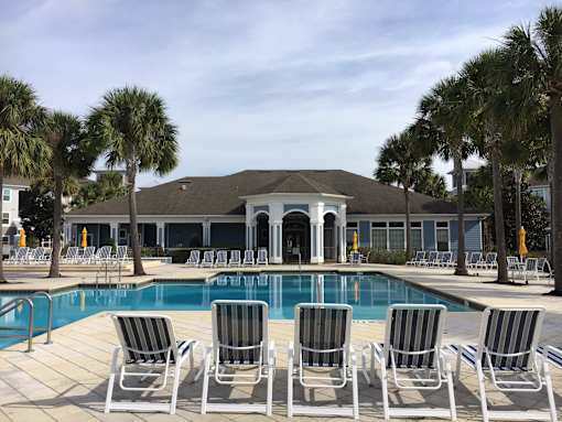 A pool with chairs and a building in the background.