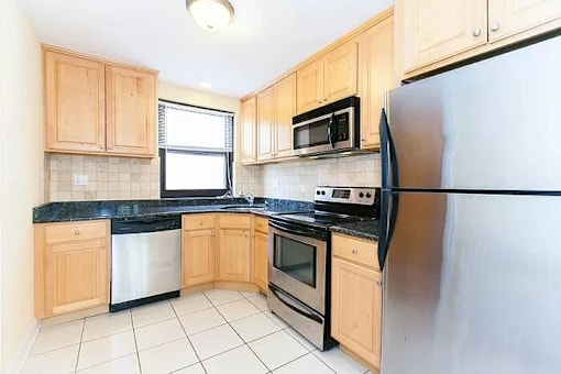 A kitchen with wooden cabinets and black countertops.