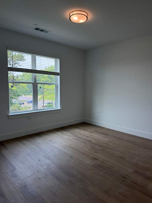 A room with a window and wooden flooring.
