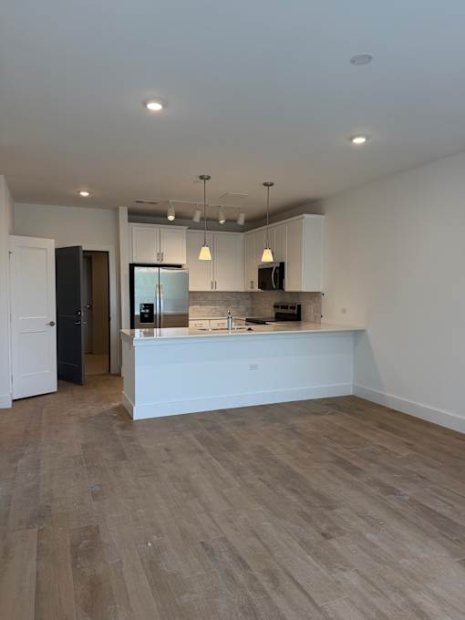 A kitchen with a white counter and wooden flooring.