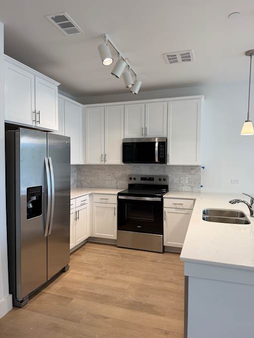 A kitchen with a stainless steel refrigerator, oven, and sink.
