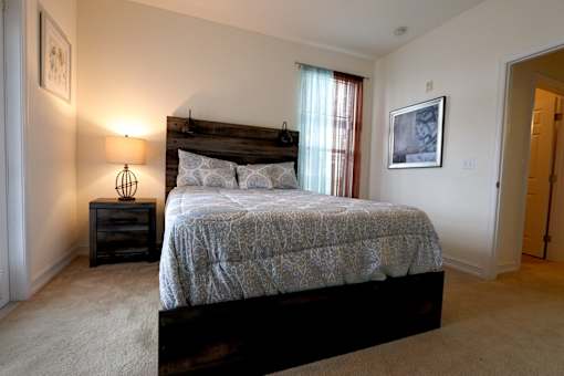 A bedroom with a bed, nightstand, and lamp.