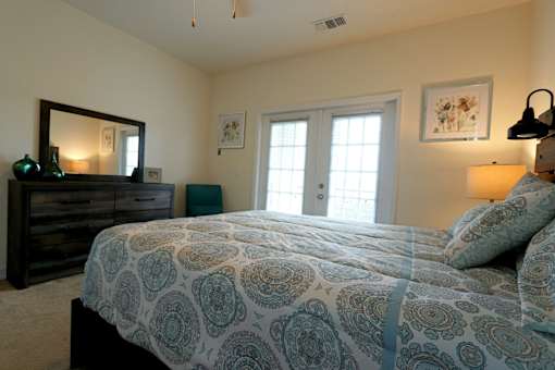 A bedroom with a bed, dresser, and mirror.