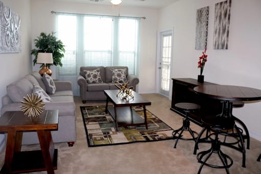 A living room with a grey couch, a coffee table, and a black piano.