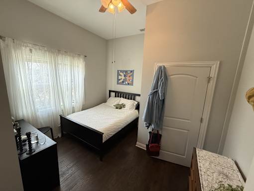 A bedroom with a bed, a dresser, and a window with curtains.