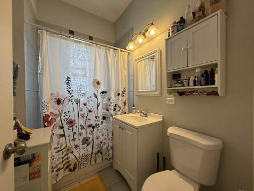 A small white bathroom with a floral shower curtain.