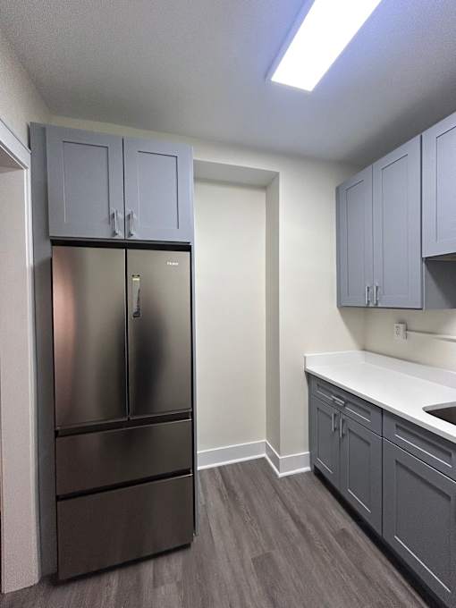 A kitchen with a stainless steel refrigerator and cabinets.