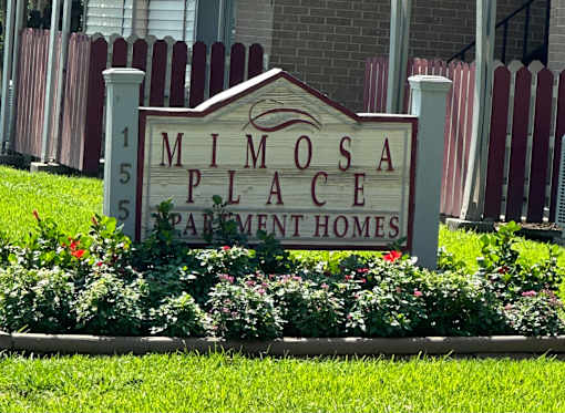 a sign in front of a building that says mimosa place apartment homes
