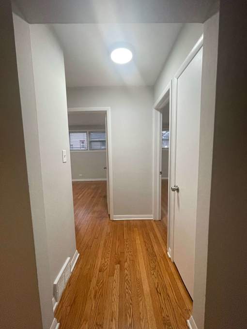A hallway with wood floors and white walls.