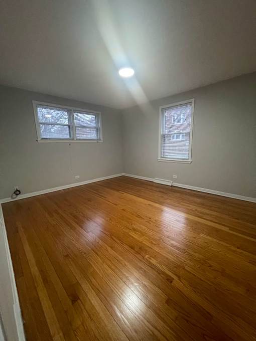 A room with wooden floors and two windows.