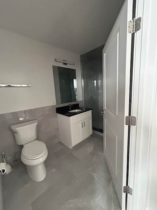 A white toilet in a bathroom with a white cabinet and a white door.