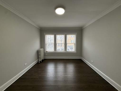 A room with a window and a radiator on the floor.