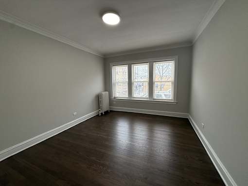 A room with a window and a radiator on the floor.