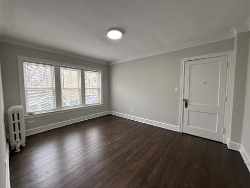 A room with a white door and a window with blinds.