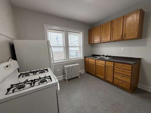 A kitchen with a white stove and wooden cabinets.