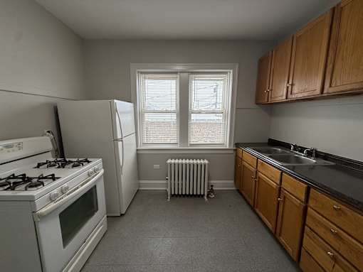 A kitchen with a white stove, white refrigerator, and wooden cabinets.