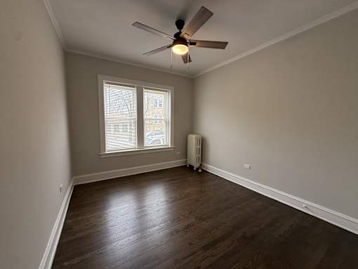 A room with a ceiling fan and a window with blinds.