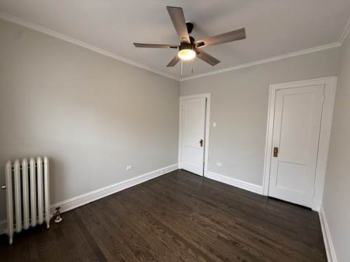 A room with a ceiling fan and a radiator on the floor.