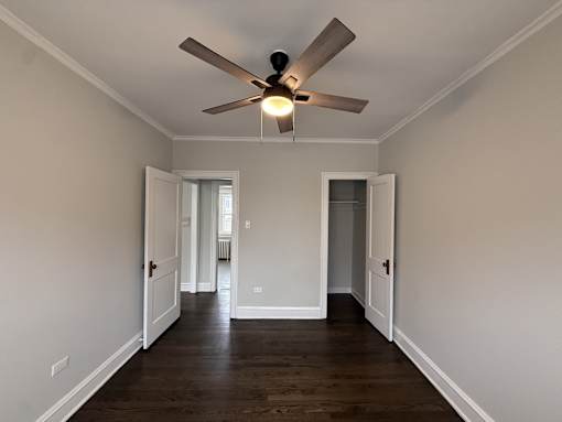 A room with a ceiling fan and wooden floors.