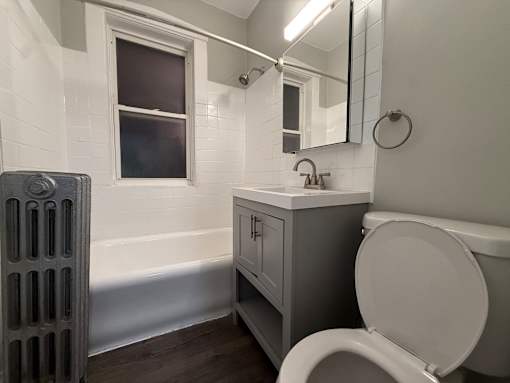 A white toilet sits in a bathroom next to a sink and a window.