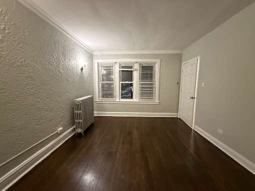 A room with a window and a radiator on the floor.