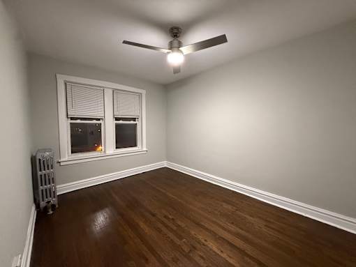 A room with a ceiling fan and a window with blinds.