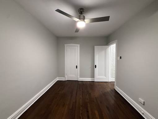 A room with a ceiling fan and two doors.