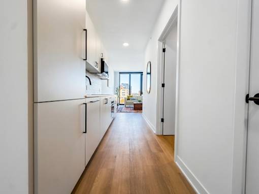 A long hallway with white walls and wood floors.