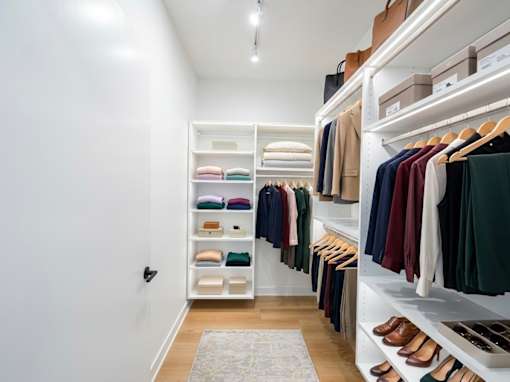 A walk-in closet with clothes and shoes neatly organized on shelves and hangers.