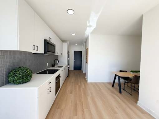 A kitchen with white cabinets and a wooden floor.