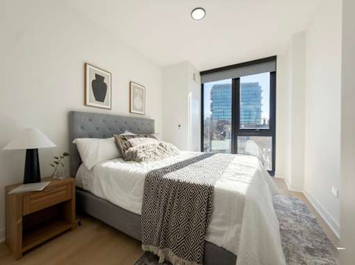 A bedroom with a large bed and a view of a city skyline.