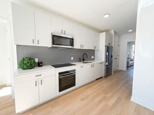 A kitchen with white cabinets and a grey backsplash.