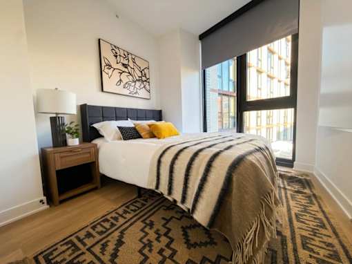 A bedroom with a bed, a nightstand, and a rug.