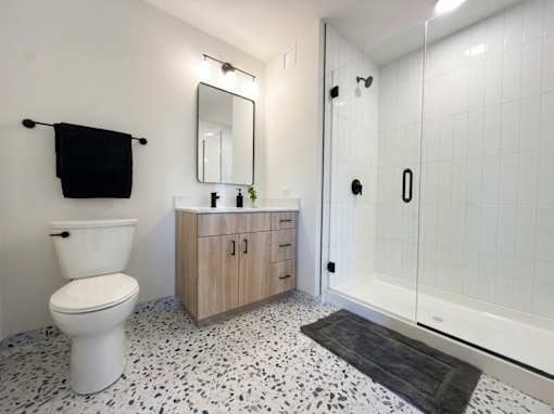 A white toilet sits next to a cabinet with a mirror above it in a bathroom.