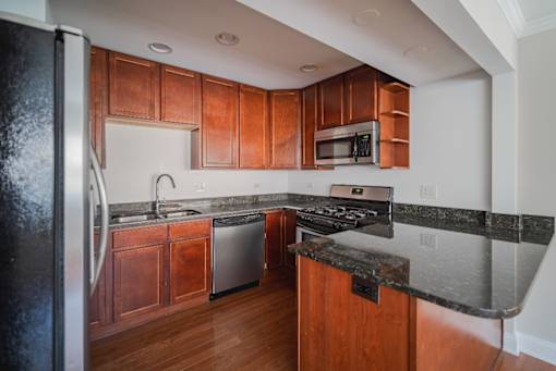 A kitchen with wooden cabinets and a black refrigerator.