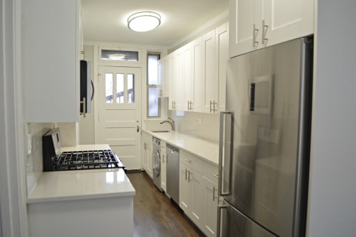 a white kitchen with stainless steel appliances and white cabinets